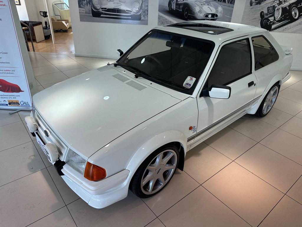 A pristine 1985 Ford Escort 1.6 Turbo RS in white, featuring its sleek 3-door design and sporty appeal.