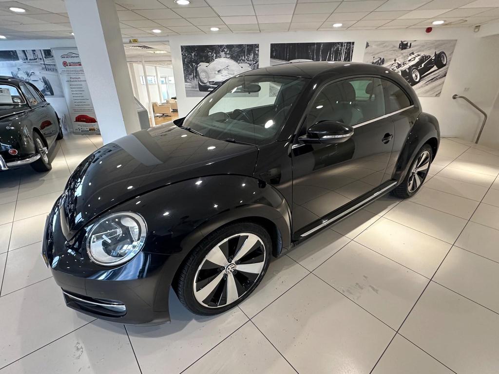 Front view of the 2013 Volkswagen Beetle in sleek black, showcasing its iconic design and alloy wheels.