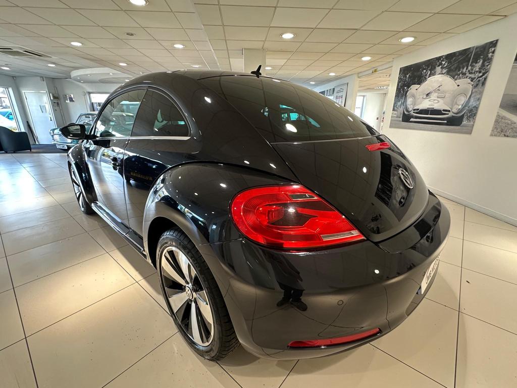Front view of the 2013 Volkswagen Beetle in sleek black, showcasing its iconic design and alloy wheels.